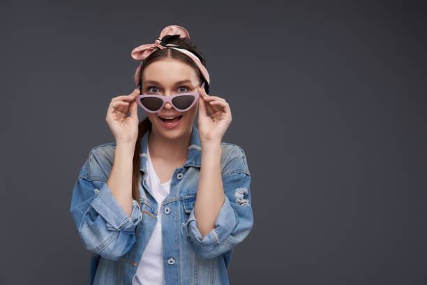 istock Charming young lady in bow headband touching stylish sunglasses 1135540351