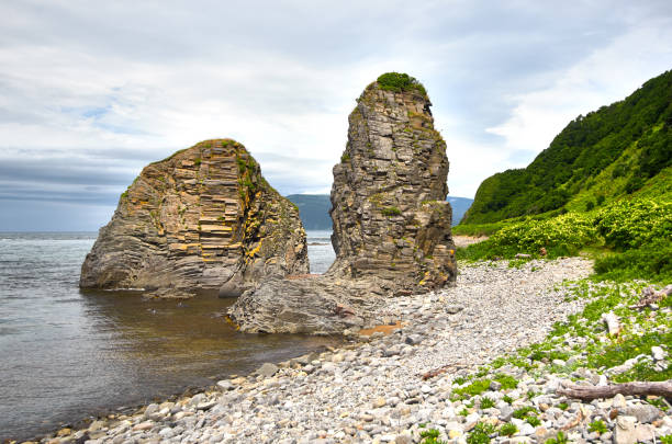 Rocky mountain coast, Kunashir island, cloudy gray gloomy sky.