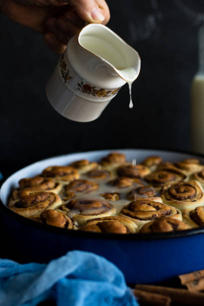istock Baker putting sugar glaze syrup on to baked cinnamon buns 1135541317