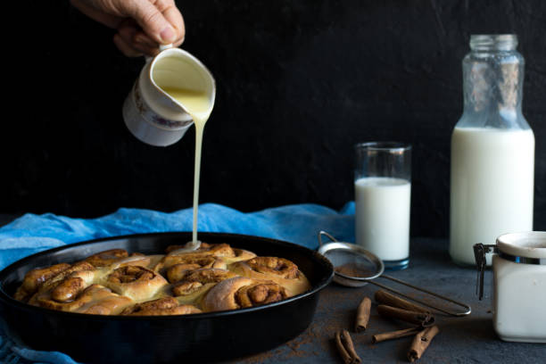 istock Baker putting sugar glaze syrup on to baked cinnamon buns 1135541473