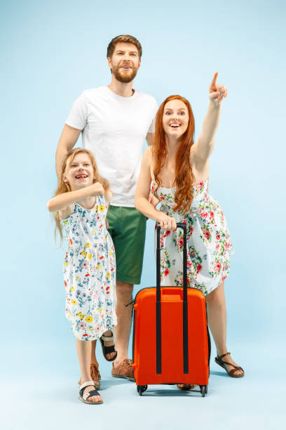 istock Happy parent with daughter and suitcase at studio isolated on blue background 1135541521