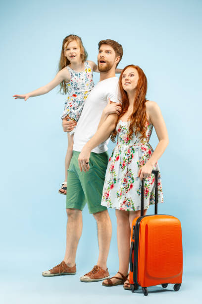 istock Happy parent with daughter and suitcase at studio isolated on blue background 1135541524