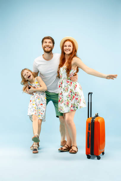 istock Happy parent with daughter and suitcase at studio isolated on blue background 1135541535