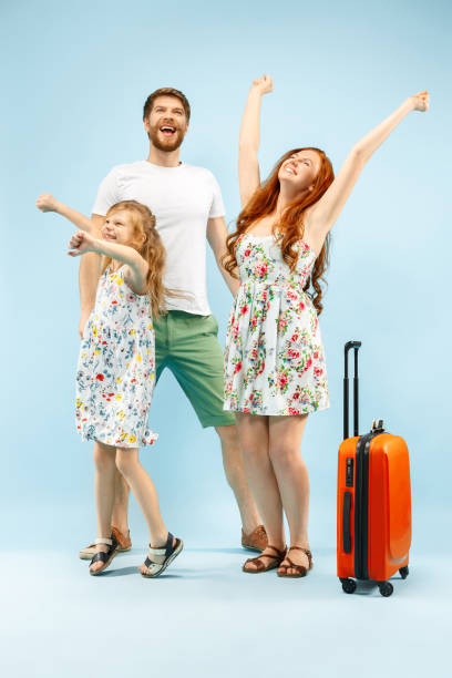 istock Happy parent with daughter and suitcase at studio isolated on blue background 1135541545