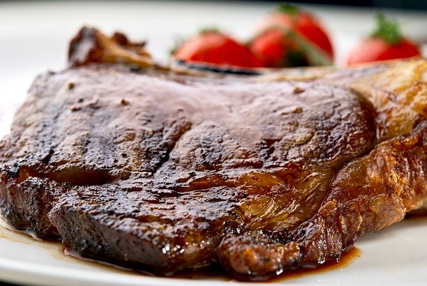 istock Macro of grilled meat ribs on white plate with tomatoes 113554389