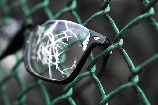 Close up of broken glasses on a metal lattice. concept of prison arrest or imprisonment.