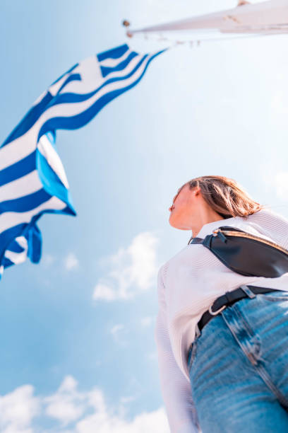 istock Young woman standing under the greek flag 1135546923