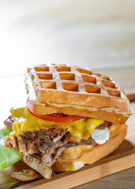istock Waffle sandwich with meat, cheese, sauce and vegetables on wooden table background 1135547347