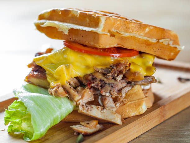 istock Waffle sandwich with meat, cheese, sauce and vegetables on wooden table background 1135547351