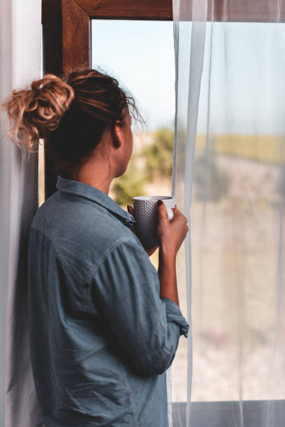 istock Young woman looking through the window 1135547388