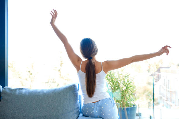 istock Stretching young woman sitting on sofa at home 1135549145