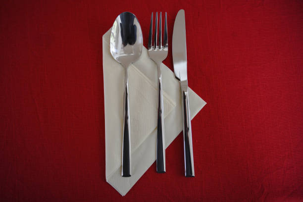 istock spoon, fork and knife on a paper napkin and a red tablecloth, table set with copy space, high angle view from above 1135551467