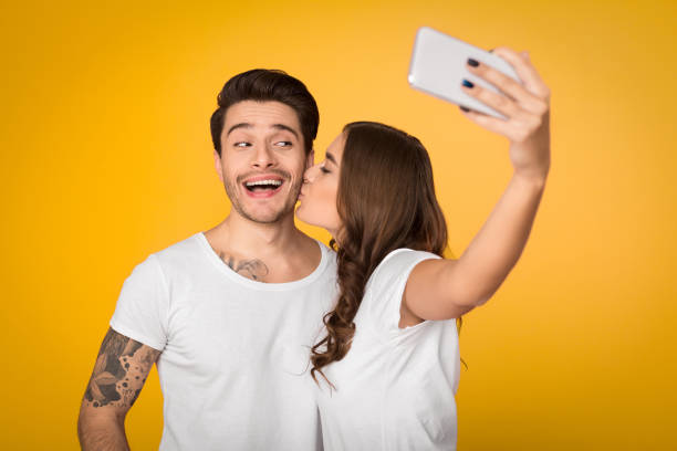 istock Lovely couple taking selfie over yellow background 1135555448