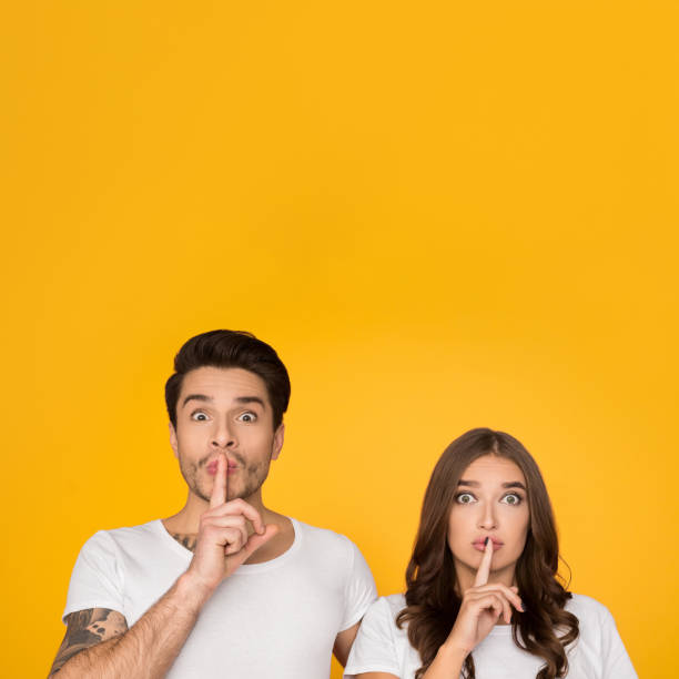 istock Young couple showing silence gesture putting finger on lips 1135555459