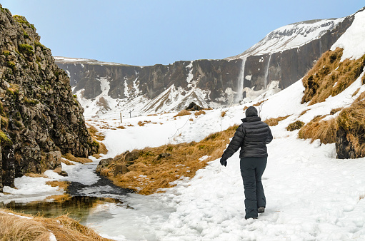 Woman admiring the beautiful winter scenery at Dverghamrer, in Southern Iceland. In the background, Foss a Sidu.
