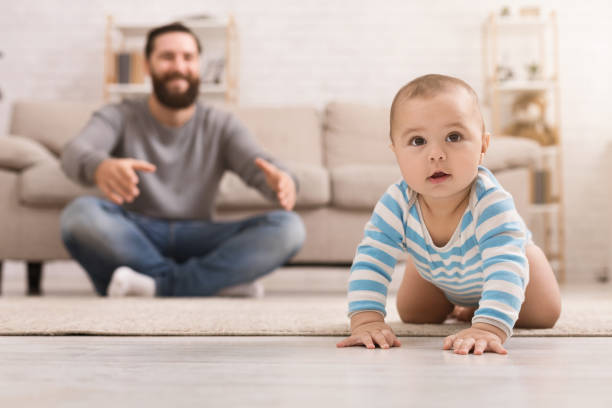 istock Adorable baby boy crawling on floor with dad 1135558862