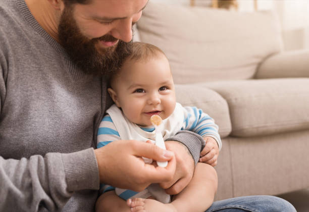 pai que alimenta seu filho bonito do bebê em casa - cereais de pequeno almoço - fotografias e filmes do acervo