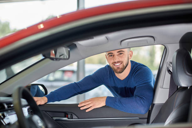 istock Attractive driver in blue sweater leaning on red vehicle. 1135560175