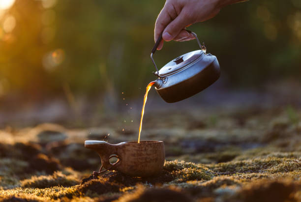 istock A man pours coffee from a kettle into a wooden kuksa mug 1135564447