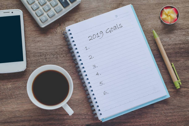 istock 2019 goals text on book note with cup of coffee, pen and smartphone. 1135566601