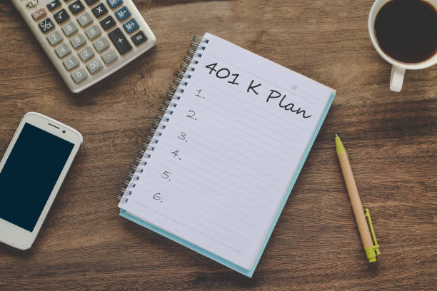istock 401K Plan text on book note with cup of coffee, pen and smartphone. 1135566610