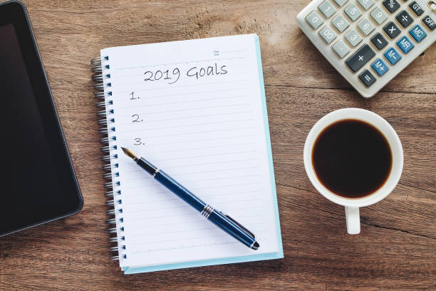 istock 2019 goals text on book note with cup of coffee, pen and smartphone. 1135566615