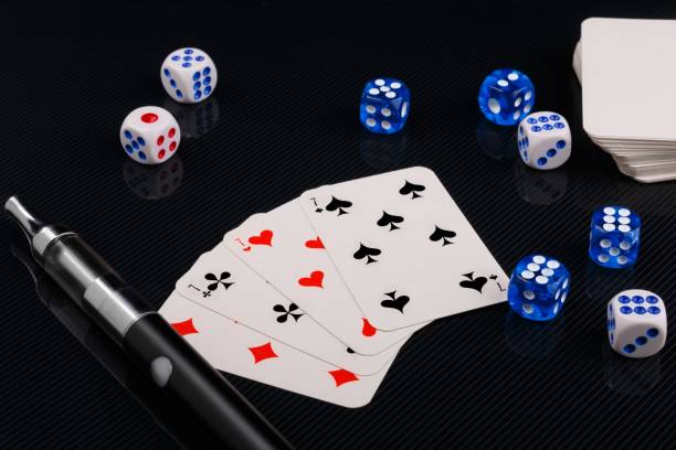 istock blue and white dices and cards with electronic sigarette on black glossy background 1135568647