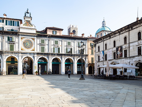 Brescia, Italy - February  21, 2019: people on Piazza della Loggia near Clock Tower Torre dell'Orologio in Brescia city. Brescia is the second largest city in Lombardy.