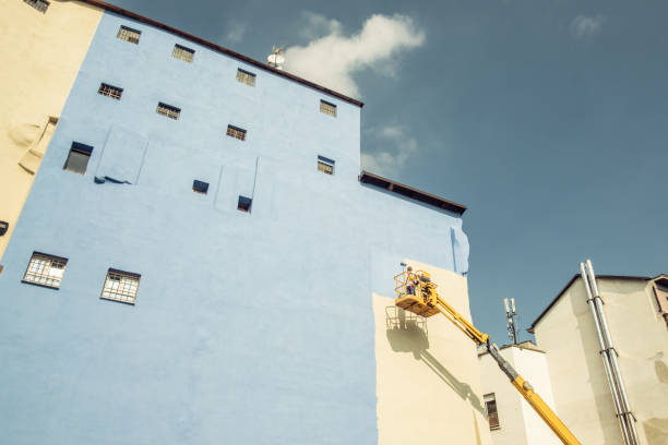 a worker painting the wall of a building - old crane blue sky imagens e fotografias de stock