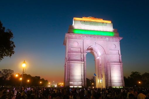 India Gate, New Delhi, India - March 10, 2019: Crowds of tourists viewing the India Gate, originally called the All India War Memorial, at night from the surrounding India Gate lawns and park, New Delhi, India.