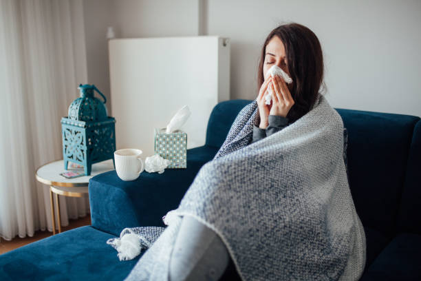 istock Sick woman blowing her nose, she covered with blanket 1135580420