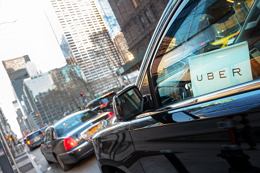 New York City, USA - March 5, 2016: Uber car service with sign in car window is waiting to pickup passengers on 6th Avenue in Manhattan, NY.