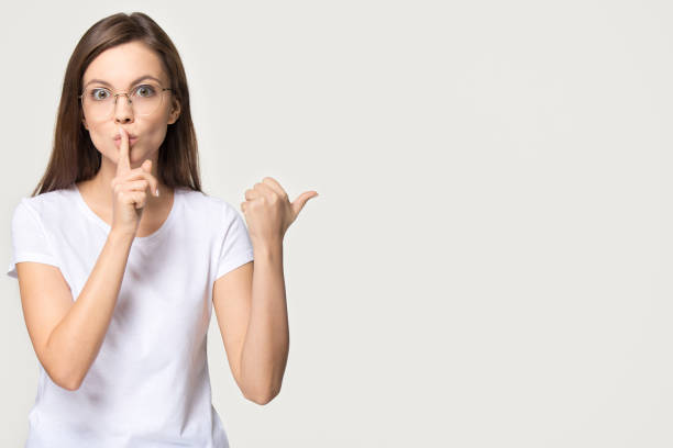 istock Silent girl holding finger on lips isolated on grey background 1135587115