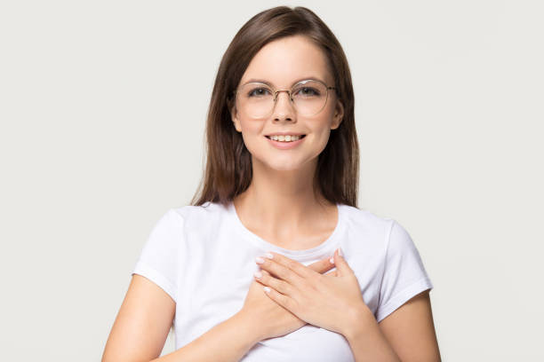 istock Grateful young woman holding hands on chest isolated on background 1135587123
