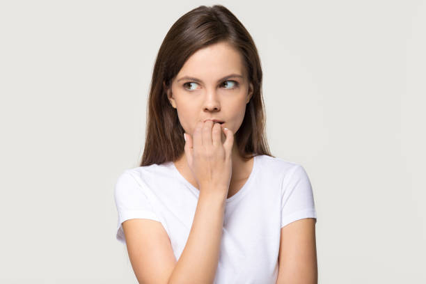 istock Nervous insecure young woman biting nails isolated on grey background 1135587136