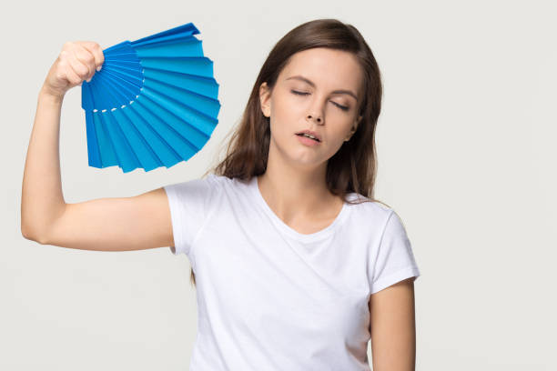 Tired young woman feel overheated suffering from heat waving fan Tired young woman feel overheated suffering from heat stroke high temperature sweating problem, sweaty girl holding waving fan cooling in hot summer weather isolated on white grey studio background overheated photos stock pictures, royalty-free photos & images