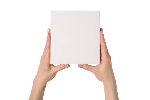 istock Small white cardboard box in female hands. Top view. Isolate 1135587939