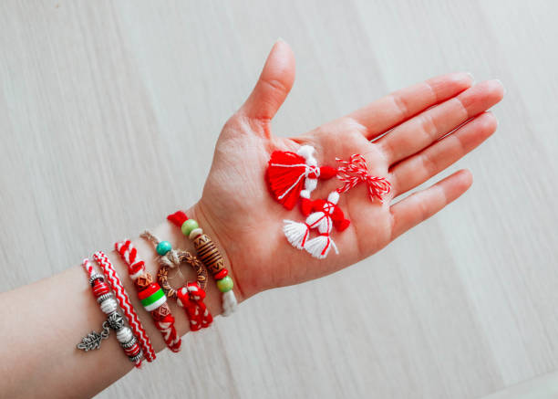 bulgarische traditionelle frühlingsdekoration martenitsa armbänder, in der hand, hölzerner hintergrund. baba marta urlaub, kulisse. - 1 2 months stock-fotos und bilder