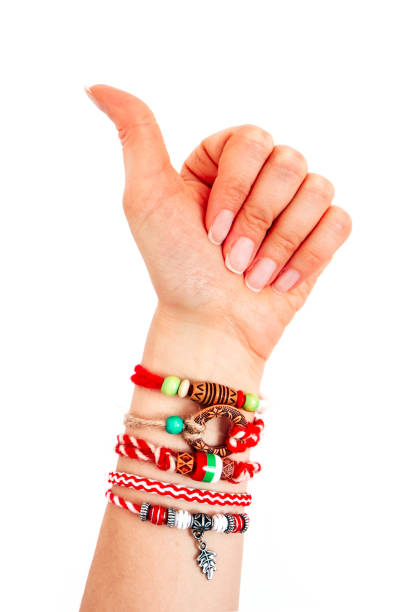 Bulgarian traditional spring decor bracelet martenitsa, pointing female hand. Baba Marta holiday, thumb up finger gesture, backdrop.