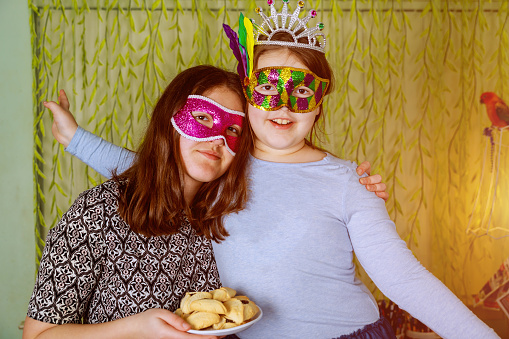 Jewish holiday Purim Happiness of fun and happy expressions In Festive Carnival Masks with hamantaschen cookies or hamans ears