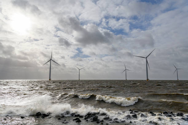 istock Wind turbines in an offshore wind park during a storm with big waves hitting the shore 1135594013