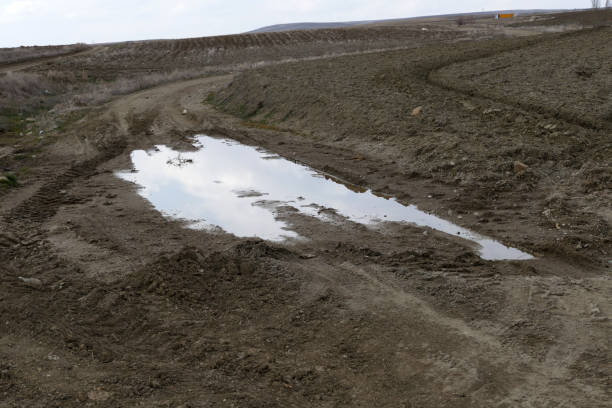 istock muddy puddle on the road, muddy bog road prevents vehicles, 1135595418