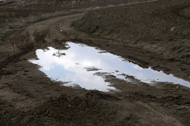 istock muddy puddle on the road, muddy bog road prevents vehicles, 1135595501