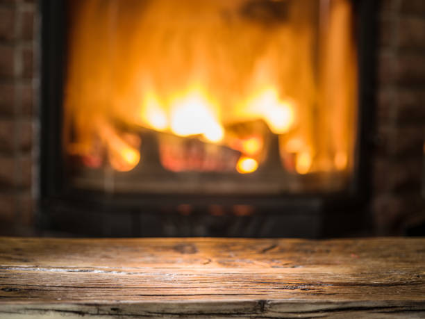 istock Old wooden table and fireplace with warm fire. 1135595622