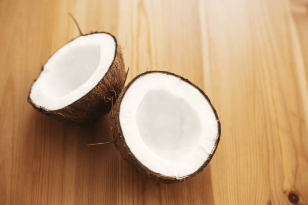 istock Halved coconut on wooden table, flat lay. Hello summer vacation concept. Space for text. Tropical background with coconut. Delicious nut, refreshing drink and oil source, tasty milk 1135598331