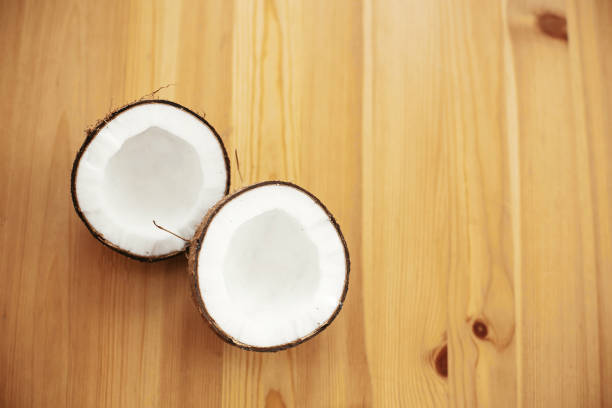 istock Halved coconut on wooden table, flat lay. Hello summer vacation concept. Space for text. Tropical background with coconut. Delicious nut, refreshing drink and oil source, tasty milk 1135598336