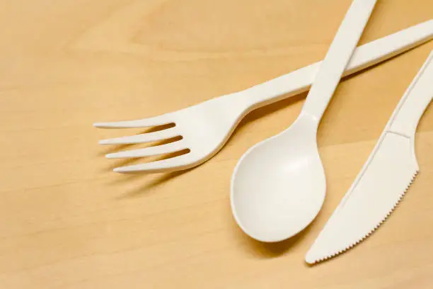 close-up of a plastic spoon and fork on wooden table