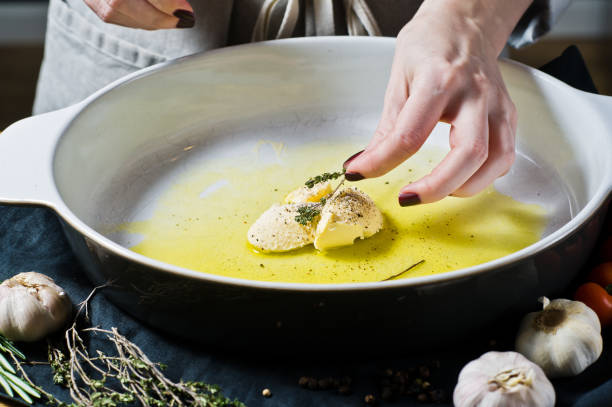 The chef adds thyme to the baking dish. The concept of cooking baked potatoes. Black background, side view, space for text, kitchen.