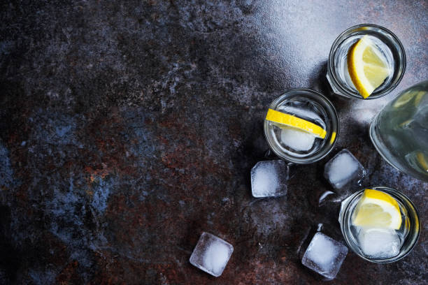 istock Cold vodka in shot glasses with lemon on stone background. Top view, copy space. 1135608981