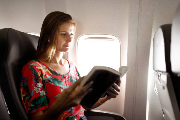 istock Woman reading book in airplane seat 1135610264